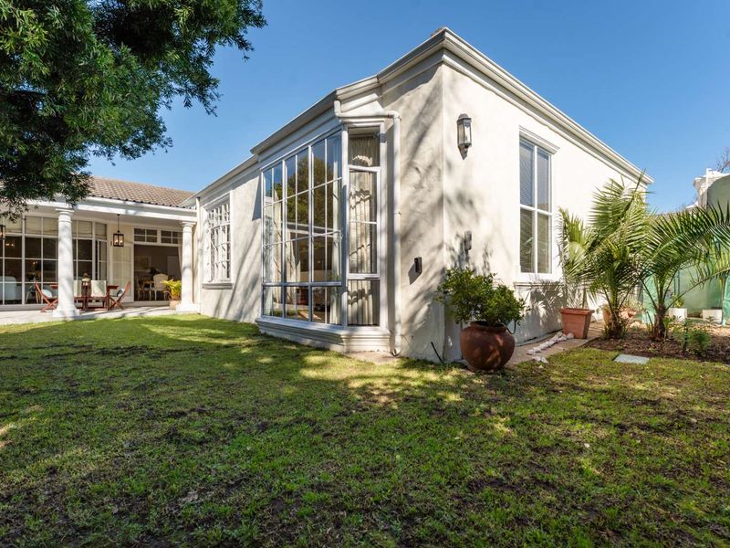 Rear view of the property featuring a well-maintained lawn, a covered patio area with columns, and a prominent bay window.