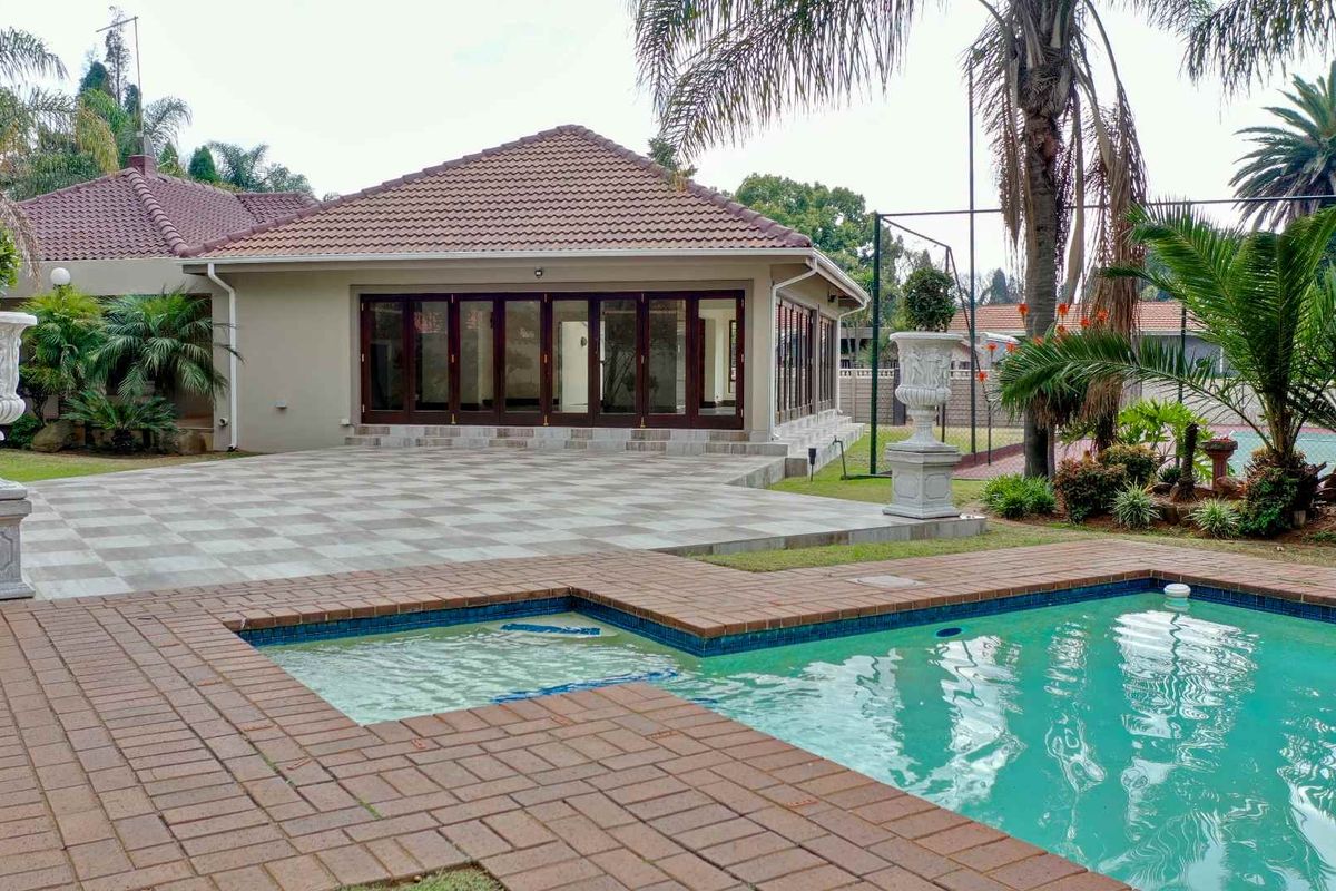 Rear exterior view featuring a swimming pool, paved patio area, and large folding glass doors leading into the main residence.