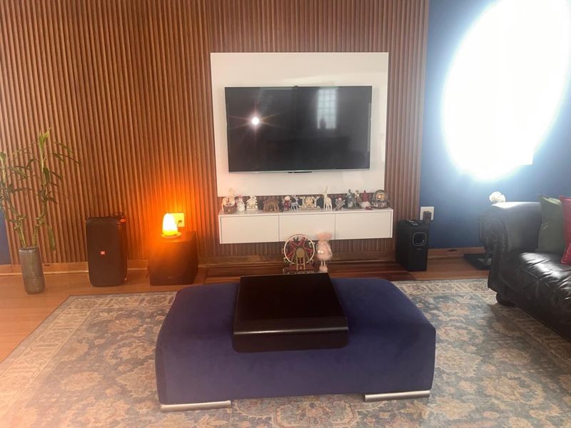 A living room featuring a modern timber slat feature wall with a built-in floating media console and polished hardwood flooring.