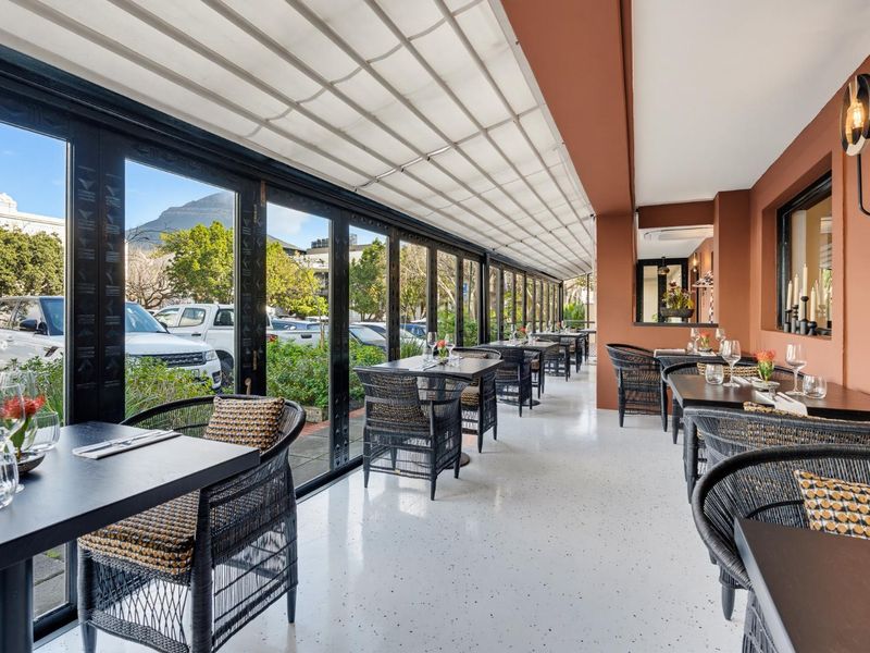A well-maintained covered patio area featuring sleek epoxy flooring, bi-fold glass doors, and a retractable awning, ideal for outdoor dining.