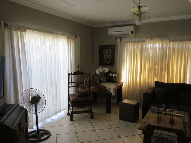 A comfortable living room featuring tiled flooring, a wall-mounted air conditioning unit, and large sliding glass doors that provide ample natural light.