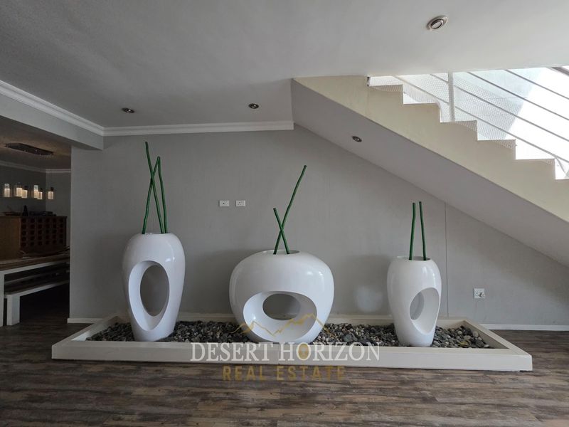 A modern living area featuring a staircase with a sleek balustrade and a built-in decorative stone feature under the stairs.