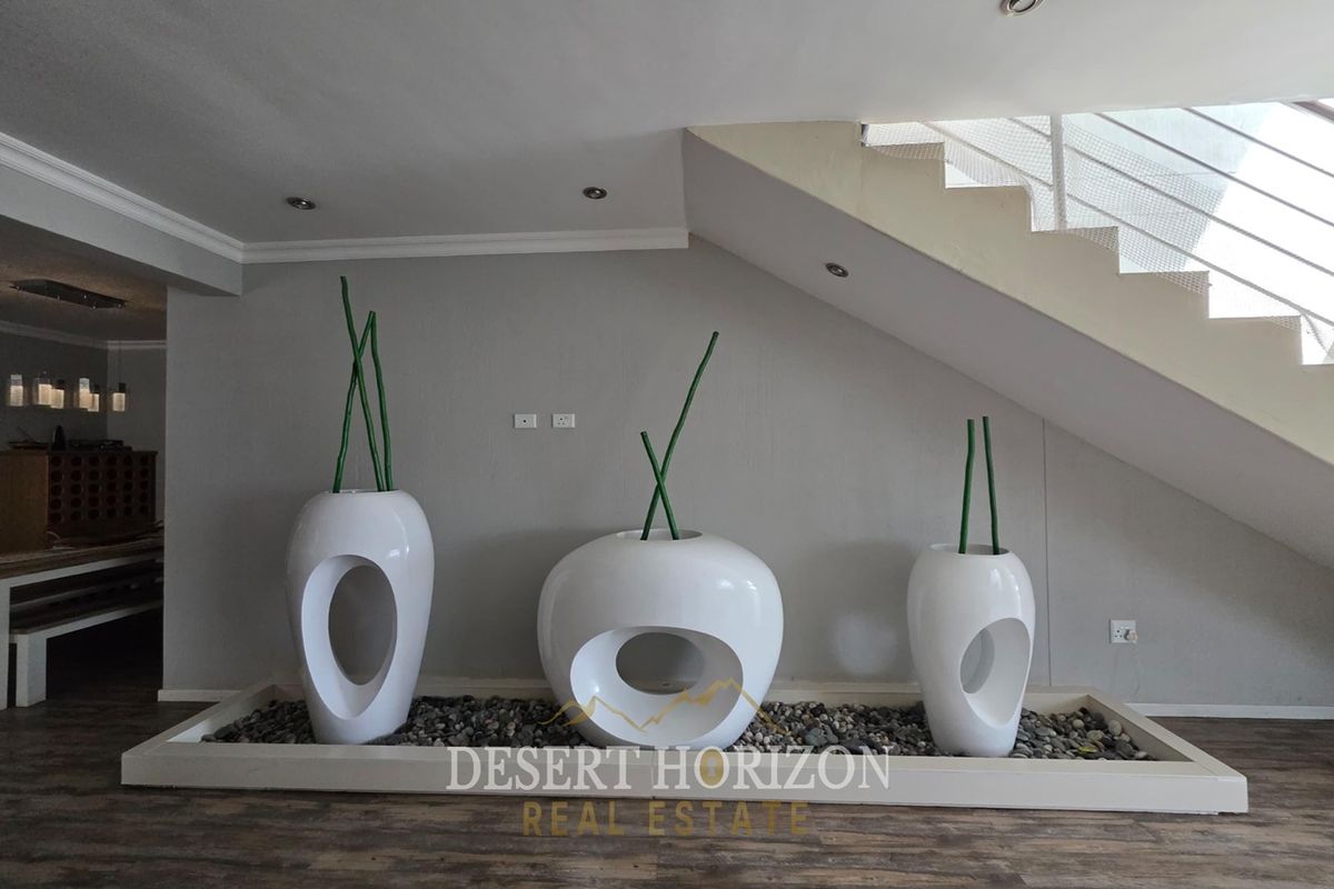 A modern living area featuring a staircase with a sleek balustrade and a built-in decorative stone feature under the stairs.
