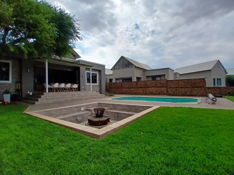 Rear garden featuring a swimming pool, sunken fire pit area, and a covered patio attached to the main residence.