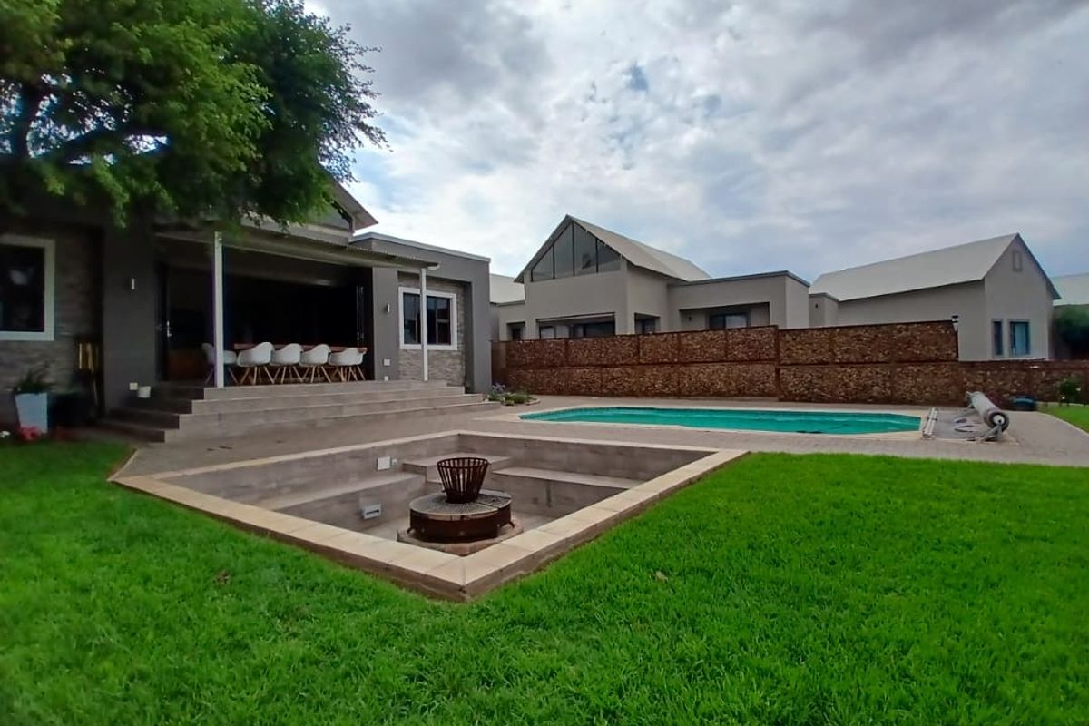 Rear garden featuring a swimming pool, sunken fire pit area, and a covered patio attached to the main residence.