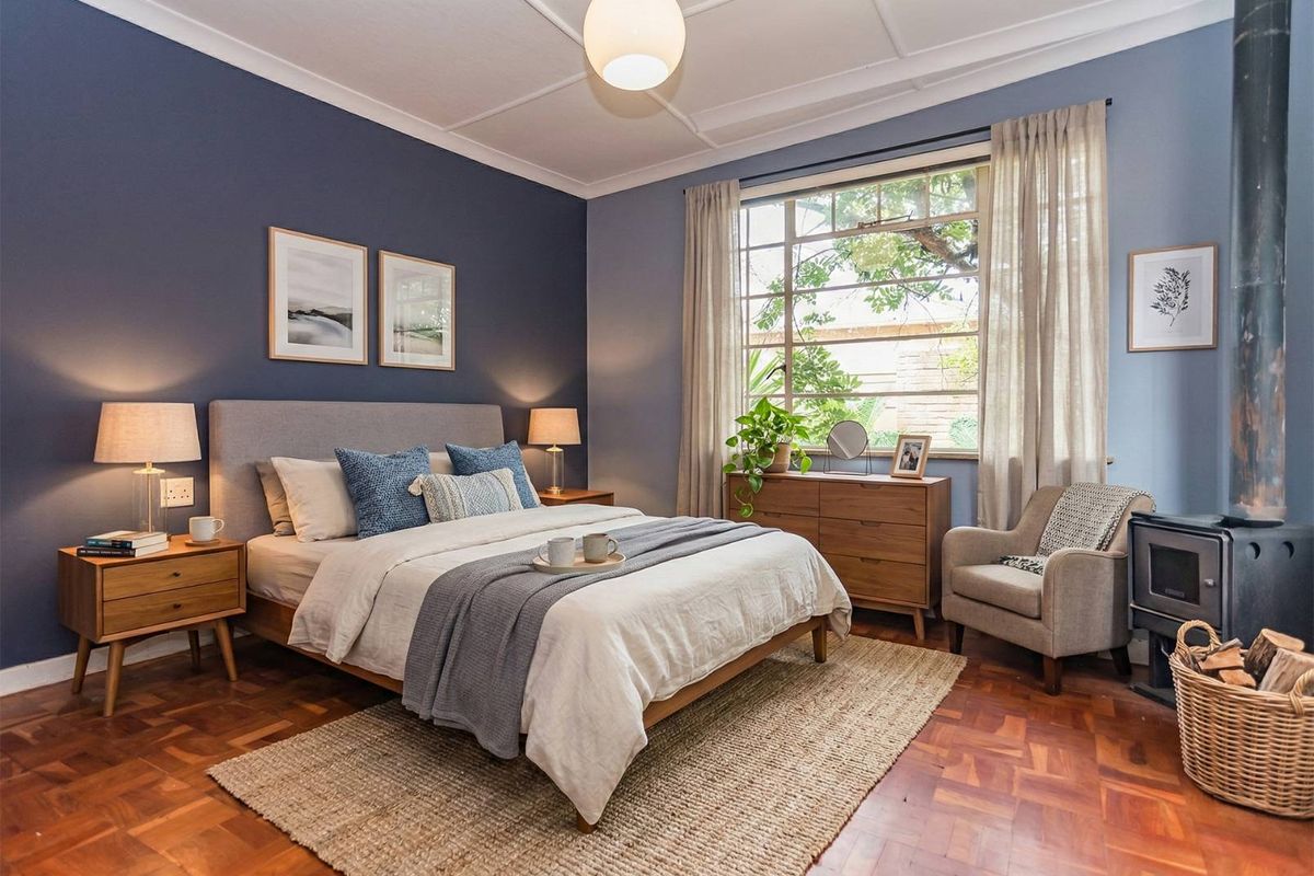 A well-maintained bedroom featuring classic parquet flooring, a cozy wood-burning stove, and large windows that provide ample natural light.