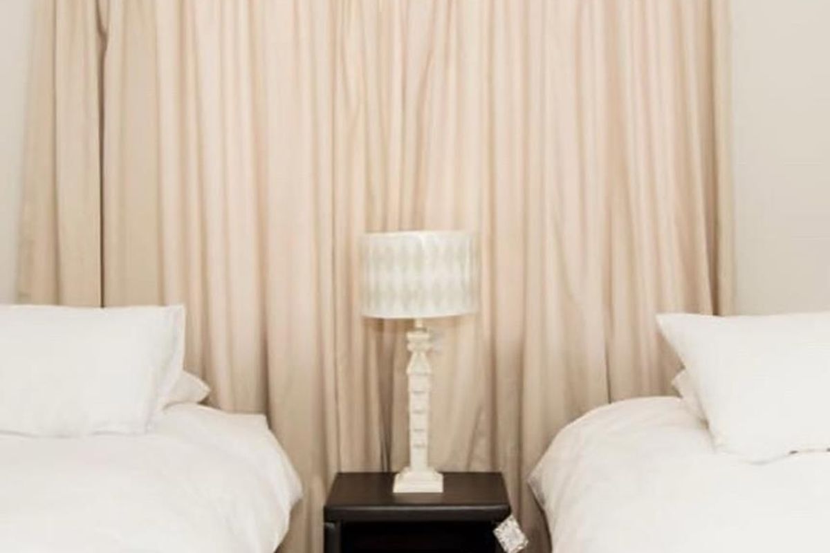 A bedroom featuring tiled flooring and neutral curtains, providing a simple and functional sleeping space.