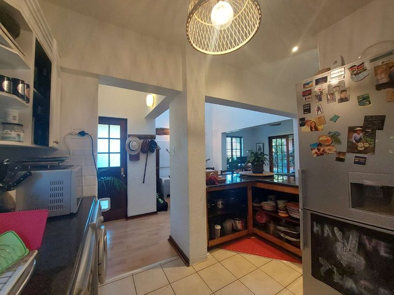 A functional kitchen area featuring tiled flooring, built-in cabinetry, and an open-plan layout connecting to the adjacent living space and entryway.