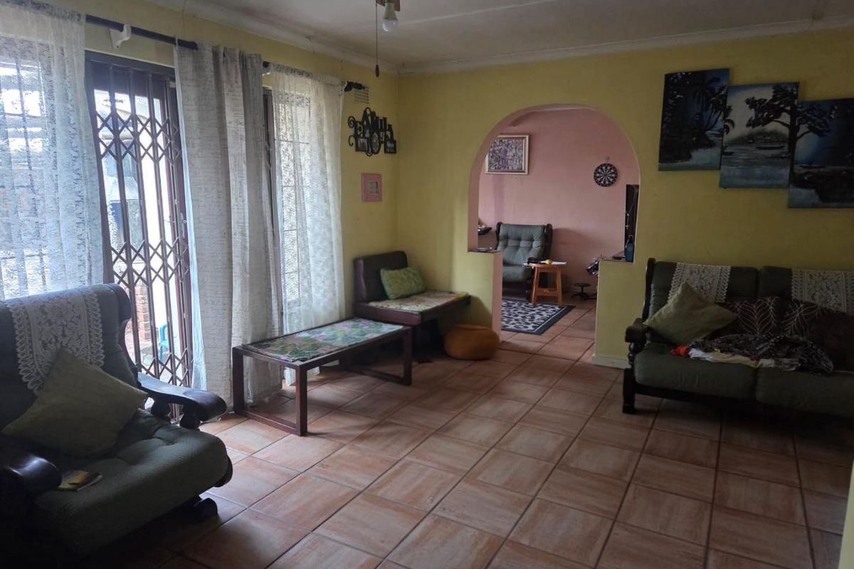 A living room featuring ceramic floor tiles, a ceiling fan, and an arched opening leading to an adjacent space.