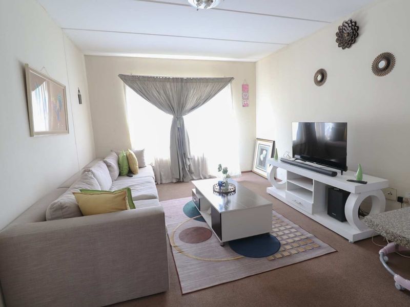 A comfortable living room featuring carpeted flooring and a large window that allows for natural light.