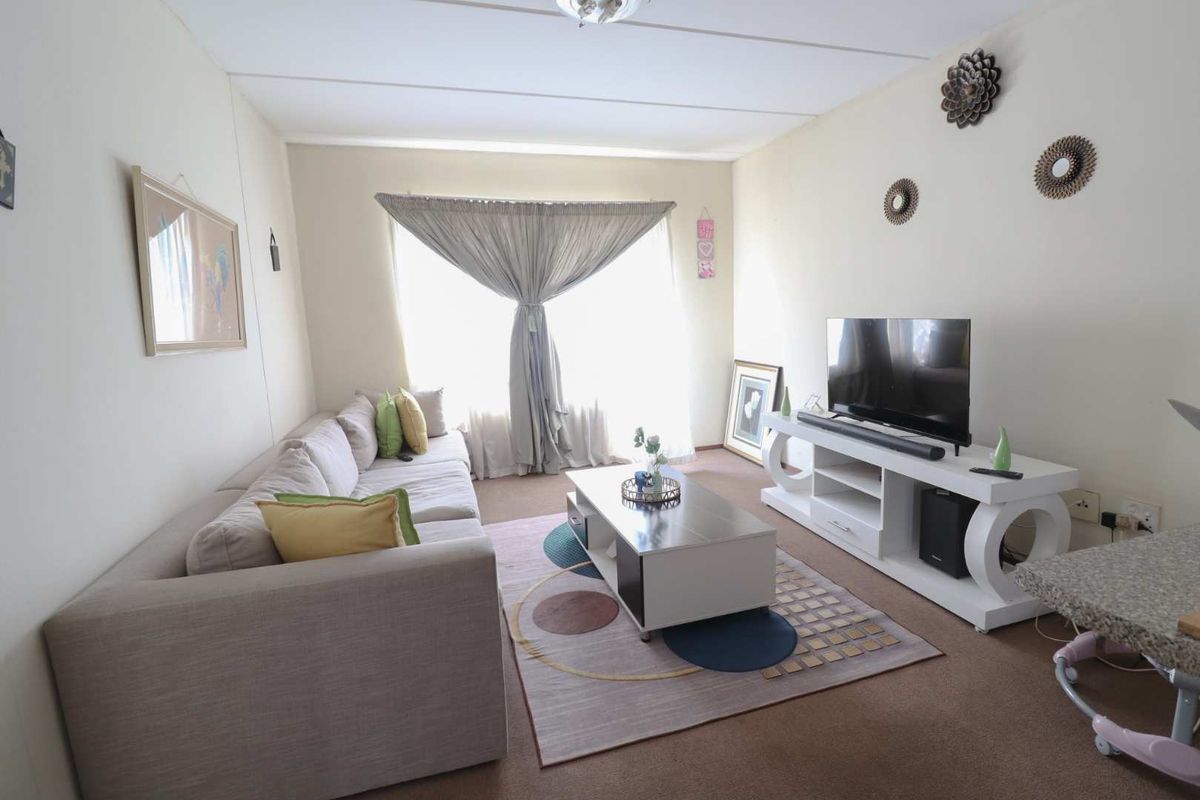 A comfortable living room featuring carpeted flooring and a large window that allows for natural light.