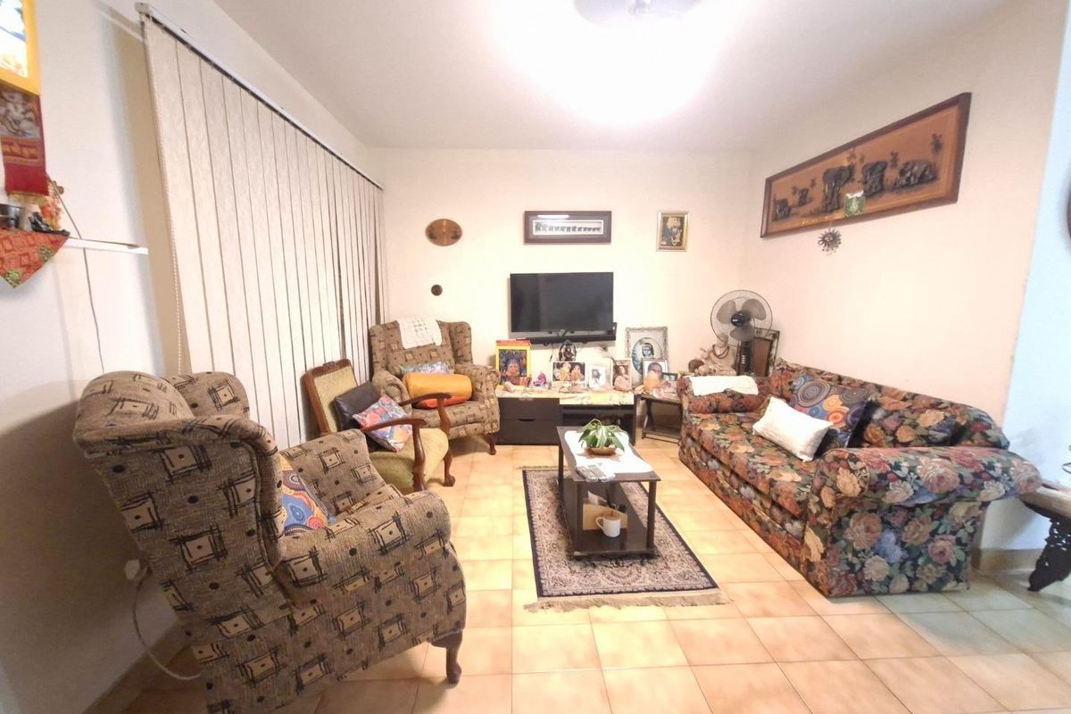 A living room featuring ceramic tile flooring and vertical blinds, providing a functional and neutral space for relaxation.