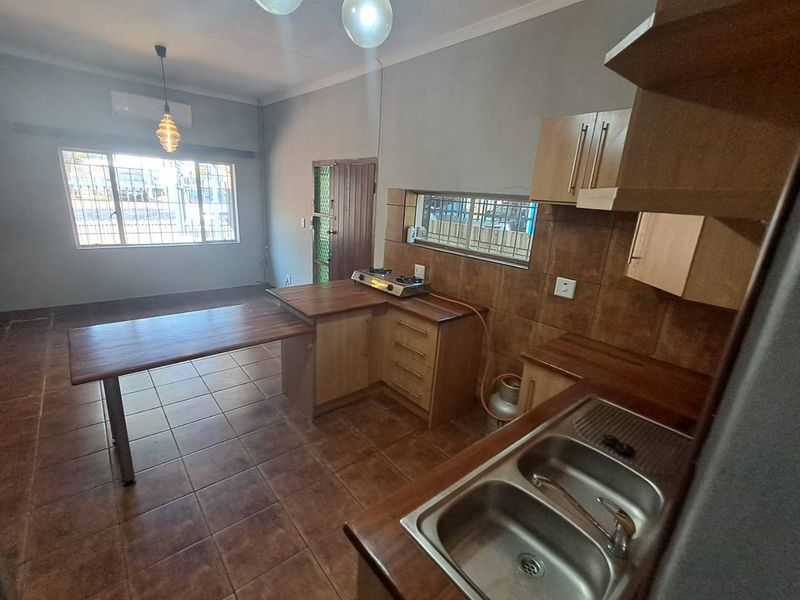 Open-plan kitchen and living area featuring tiled flooring, built-in cabinetry, a gas hob, and an air conditioning unit.