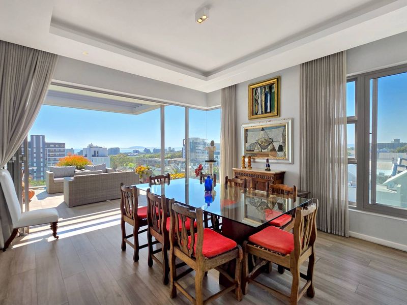 Bright dining area featuring floor-to-ceiling windows, recessed ceiling lighting, and seamless access to a spacious balcony with panoramic city and ocean views.