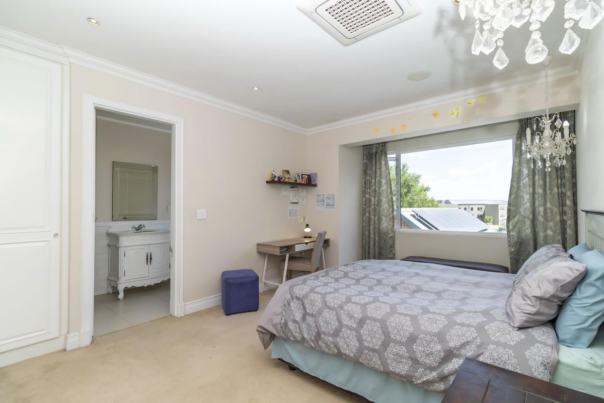 Spacious bedroom featuring neutral carpeting, crown molding, recessed lighting, and an integrated air conditioning unit, with an adjoining en-suite bathroom.