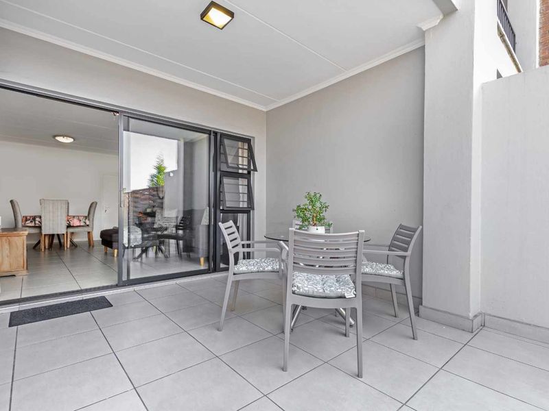 A clean, covered patio area featuring light-colored floor tiles and a large sliding glass door providing seamless access to the interior living space.