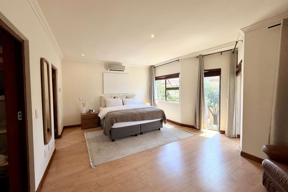 Spacious bedroom featuring laminate flooring, recessed lighting, an air conditioning unit, and built-in cupboards with access to natural light.