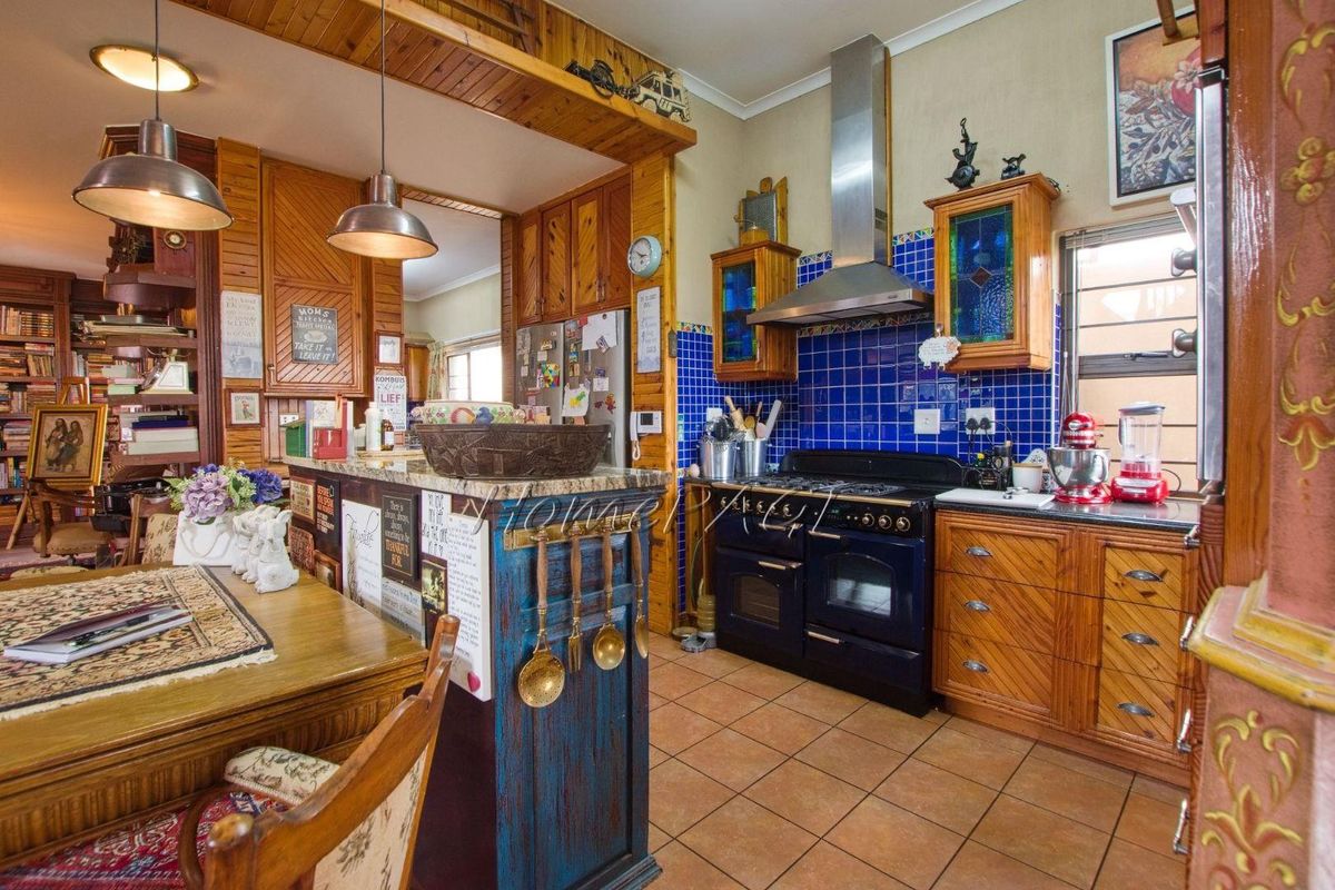 A rustic-style kitchen featuring wooden cabinetry, a blue tiled backsplash, a built-in gas range with extractor hood, and a breakfast bar counter.