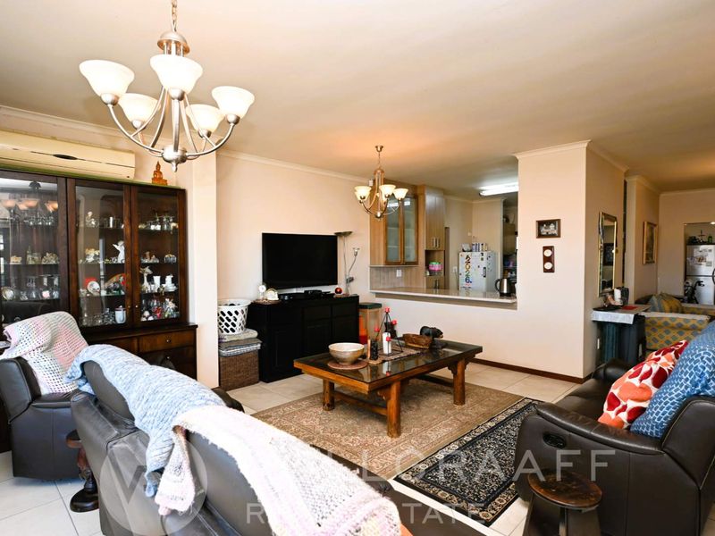 Spacious open-plan living area featuring tiled flooring, a breakfast bar connecting to the kitchen, and integrated air conditioning.
