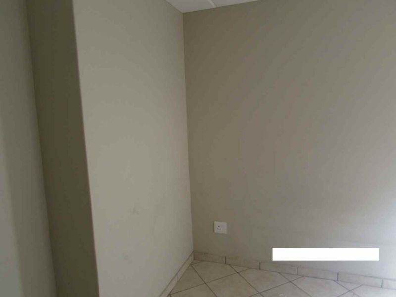 An empty corner space featuring neutral wall paint and tiled flooring, suitable for various residential uses.