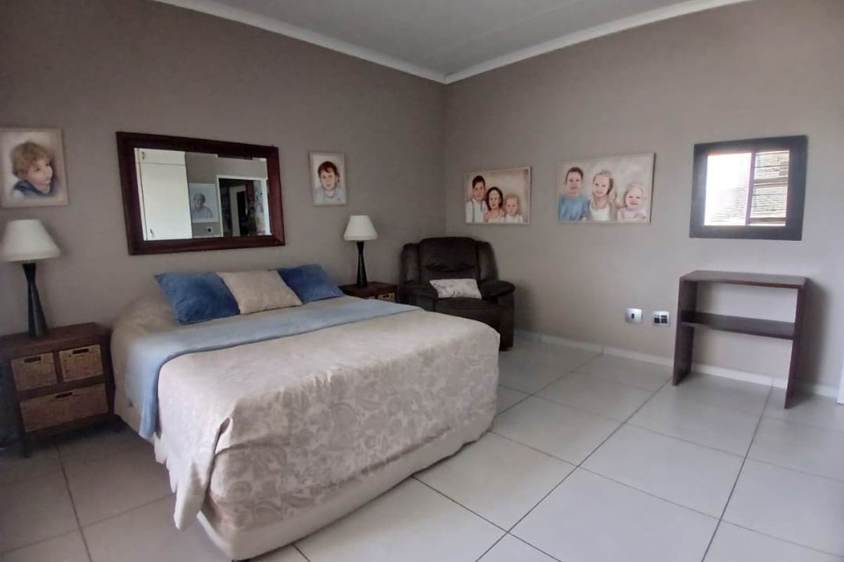 Spacious bedroom featuring neutral wall tones, large format floor tiles, and a built-in window.