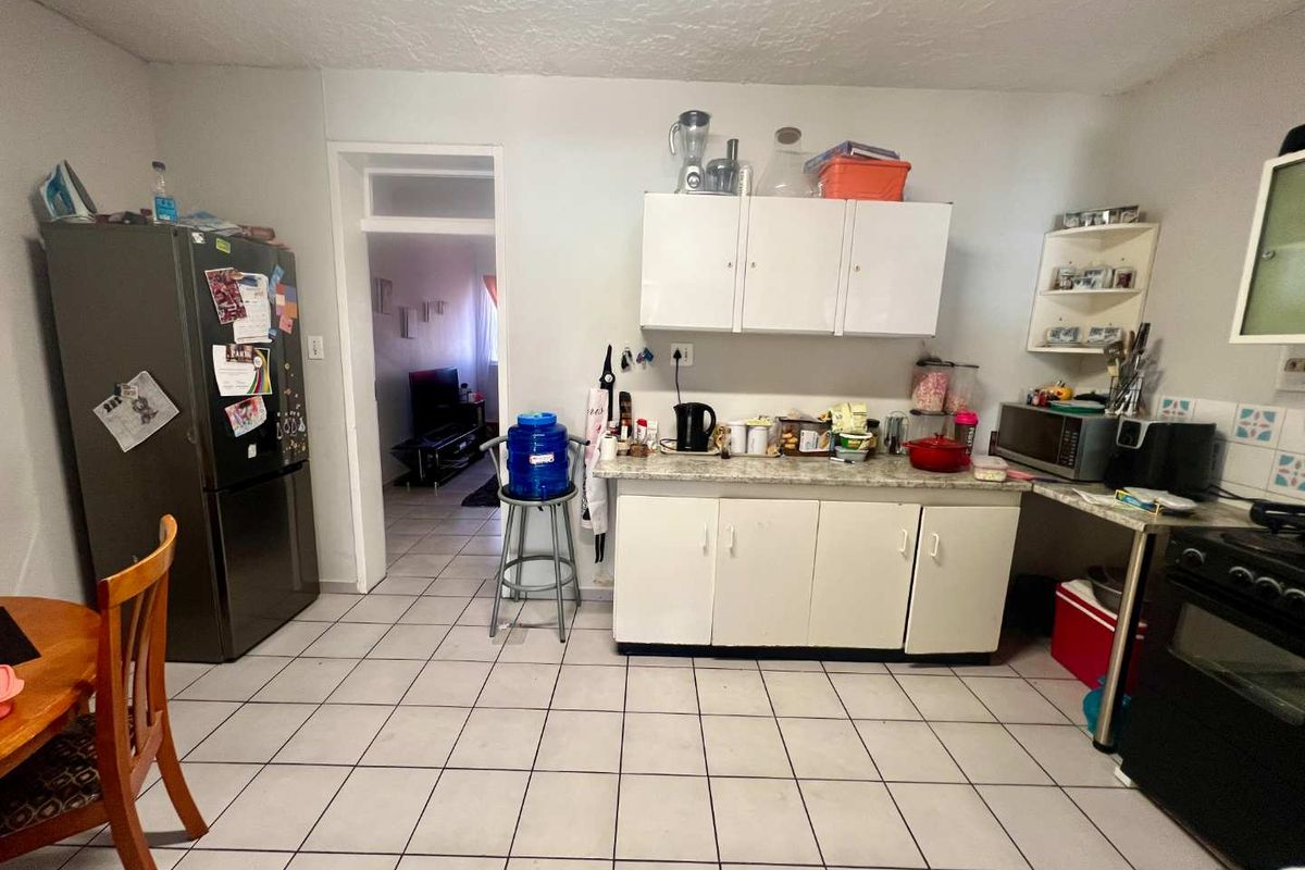 A functional kitchen area featuring white cabinetry, laminate countertops, and tiled flooring, providing a practical space for daily meal preparation.