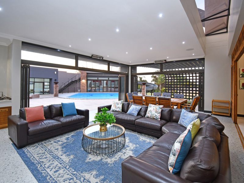 Spacious open-plan living area featuring seamless indoor-outdoor flow through bi-fold doors, terrazzo flooring, recessed lighting, and a convenient built-in wet bar.