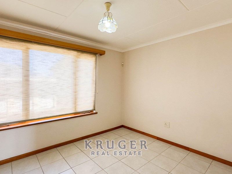 A bright, empty bedroom featuring neutral tiled flooring, a timber window sill, and a fitted roller blind, ready for personalization.