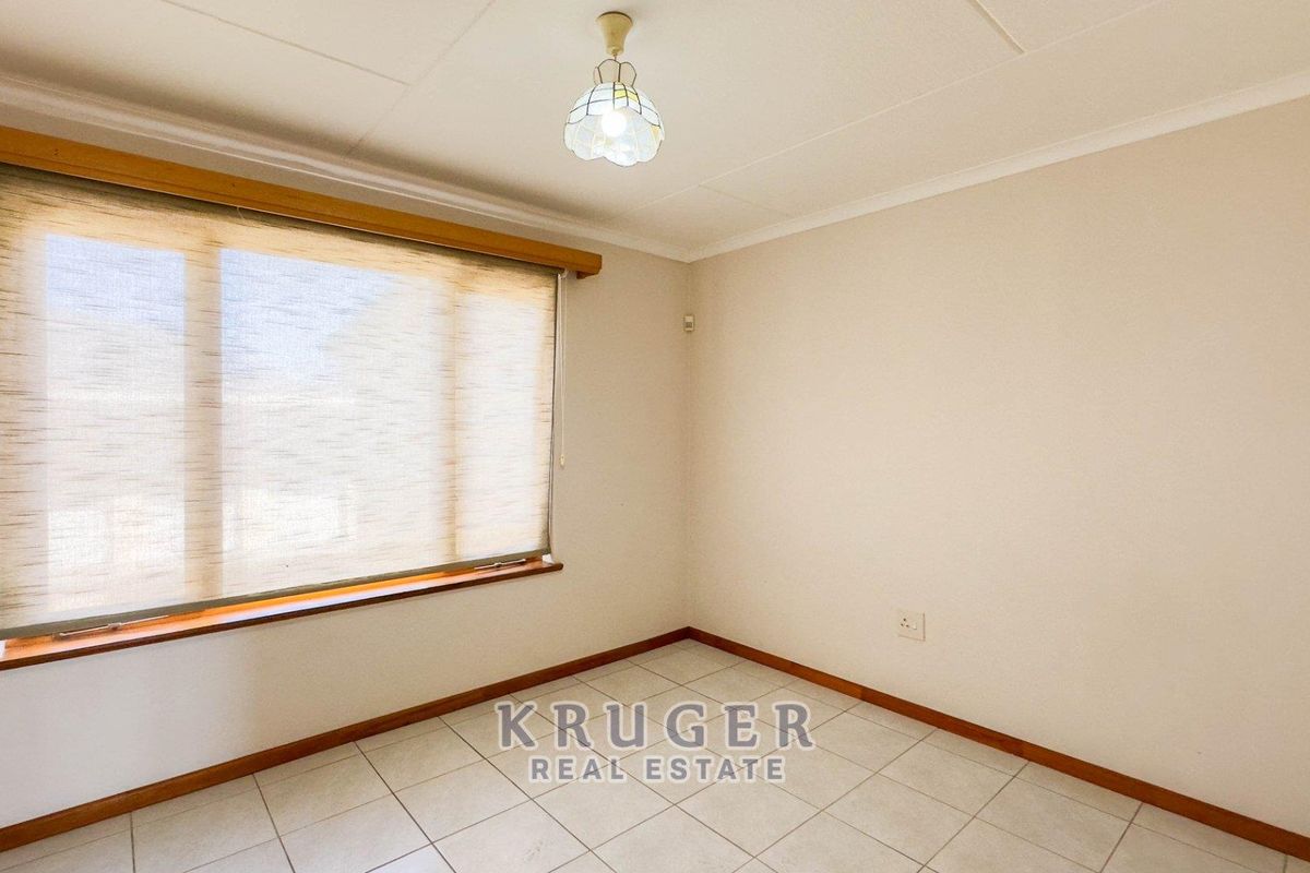 A bright, empty bedroom featuring neutral tiled flooring, a timber window sill, and a fitted roller blind, ready for personalization.