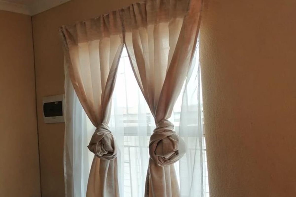 A view of a window featuring a curtain rod and security bars, set within a neutral-toned room.