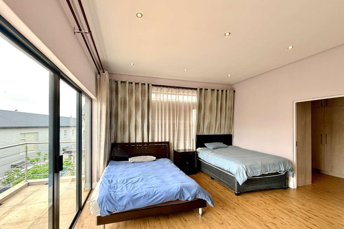 Spacious bedroom featuring laminate flooring, recessed lighting, and large sliding glass doors providing access to an outdoor balcony area.