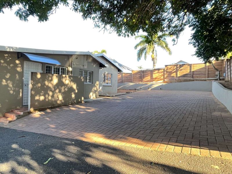Spacious paved driveway and front exterior area featuring a retaining wall and secure boundary fencing.