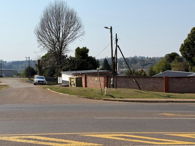 A street-level view showing the property boundary, brick walling, and surrounding road infrastructure in a mixed-use area.