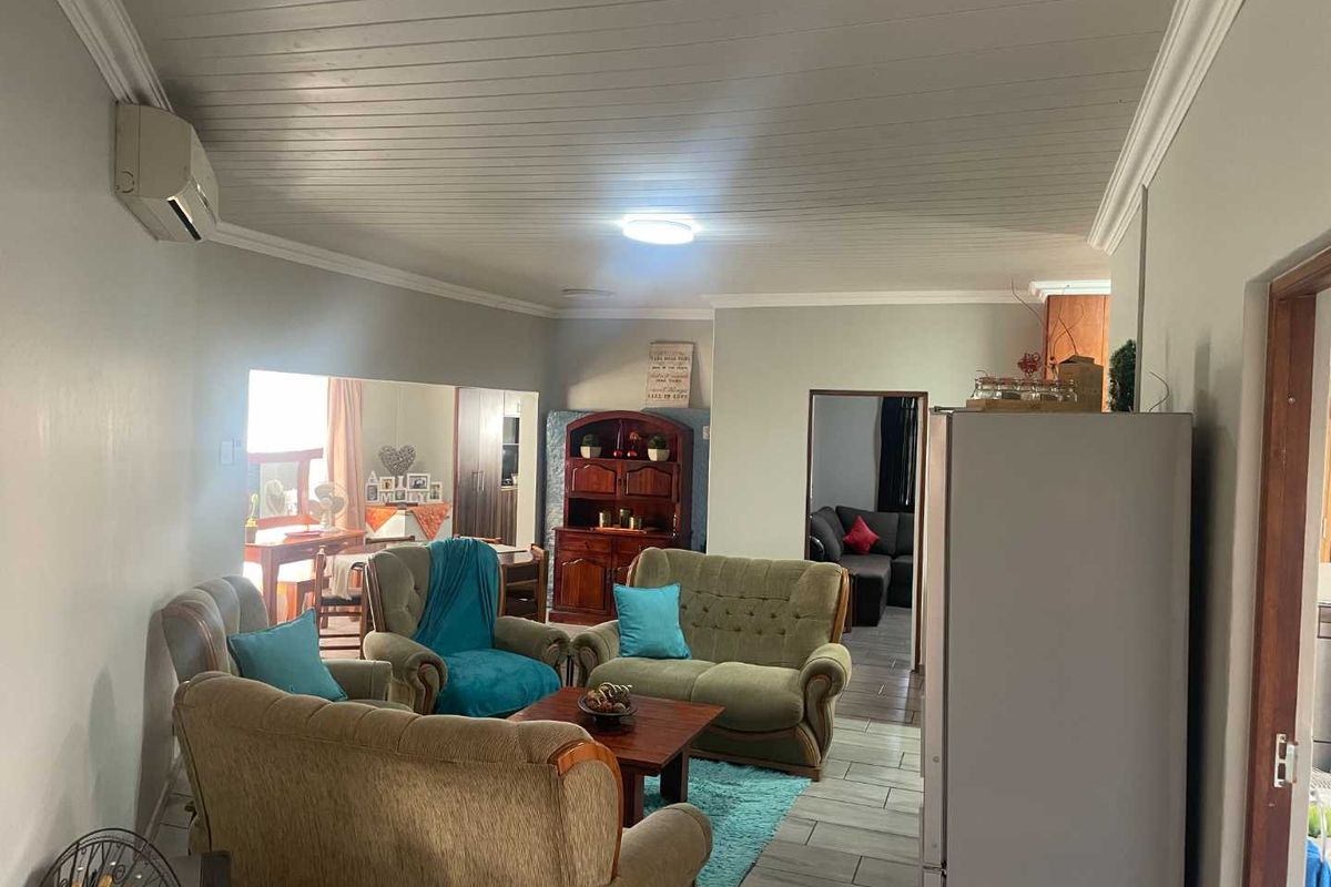 A living room featuring tiled flooring, a tongue and groove ceiling with crown molding, and a wall-mounted air conditioning unit.