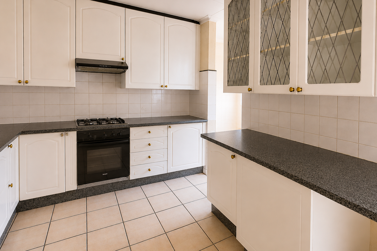 A functional kitchen featuring white cabinetry, dark laminate countertops, a built-in oven, gas hob, extractor fan, and tiled flooring.