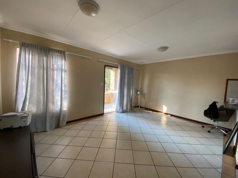 Spacious living area featuring neutral wall tones, ceramic floor tiles, and direct access to an outdoor balcony through a sliding glass door.