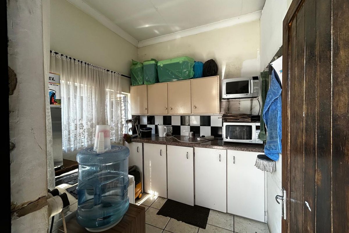 A compact kitchen featuring dated cabinetry, tiled backsplash, and built-in microwave space, offering potential for a modern renovation.