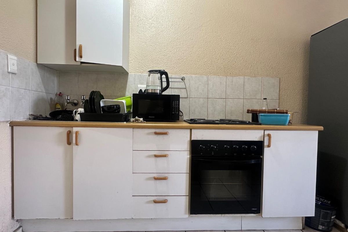 A functional kitchen area featuring white cabinetry, a built-in oven, a gas hob, and tiled splashbacks.