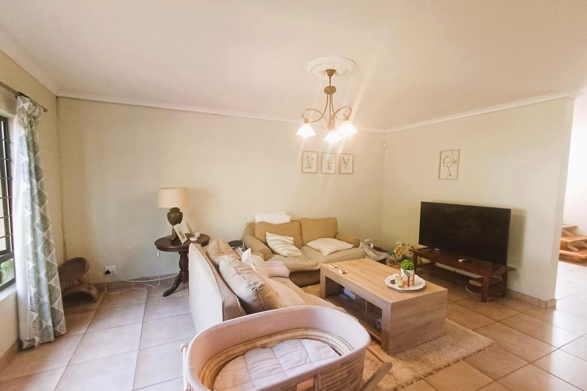 A comfortable living room featuring ceramic floor tiles, decorative ceiling rose, and coving, providing a neutral base for interior updates.
