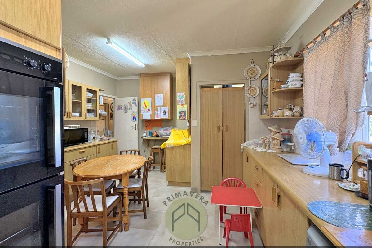 A functional kitchen featuring light wood cabinetry, built-in double oven, and tiled flooring with an integrated dining area.