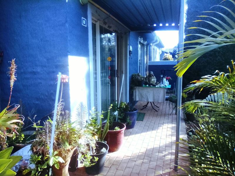 A covered patio area featuring paved flooring and sliding glass door access to the interior of the townhouse.