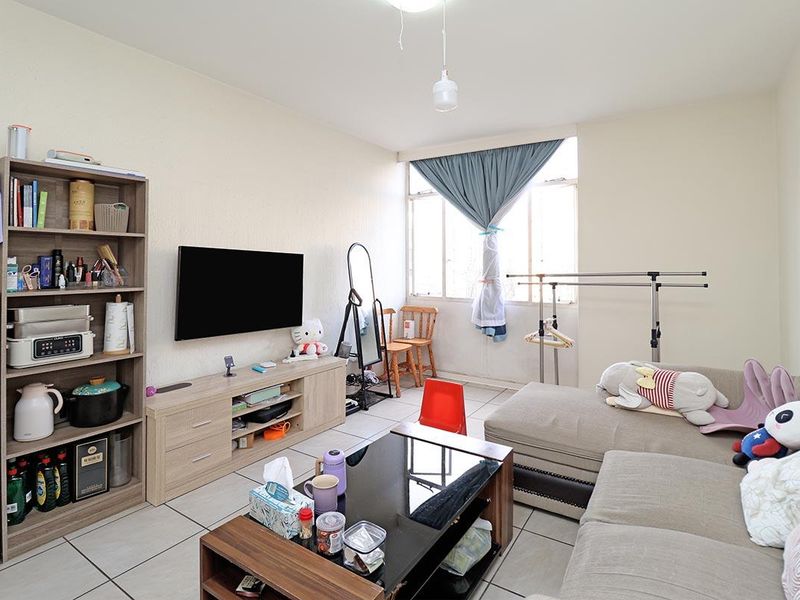 A functional living room featuring tiled flooring and a large window, providing natural light to the space.