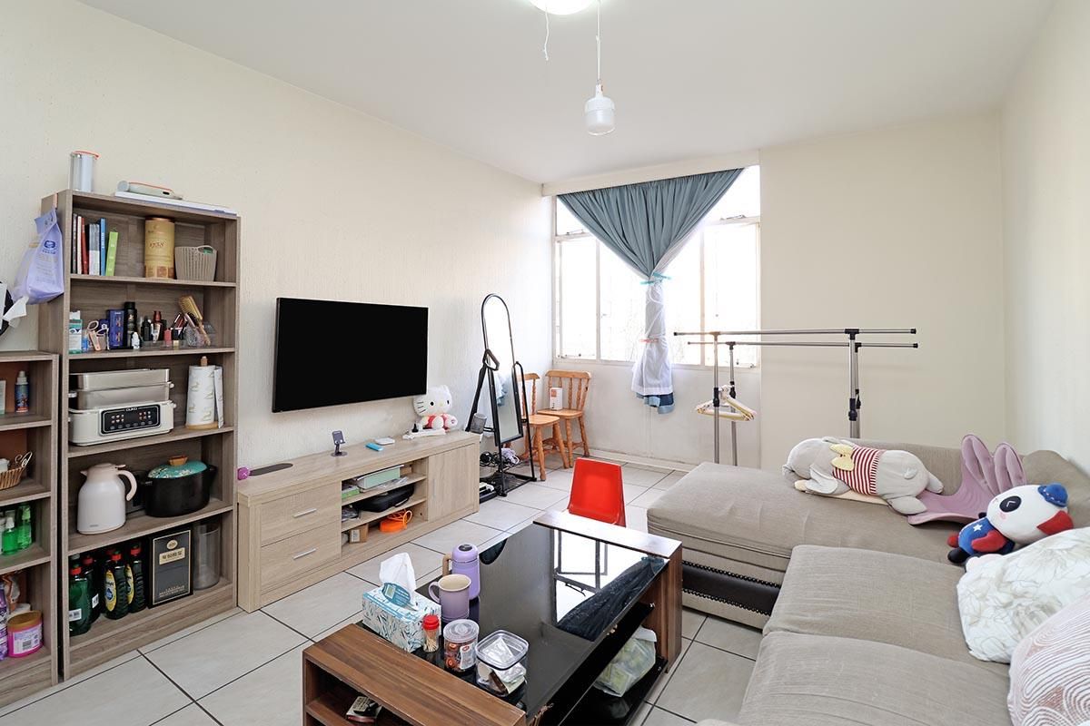 A functional living room featuring tiled flooring and a large window, providing natural light to the space.