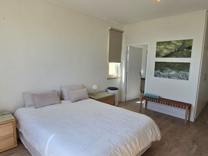A well-lit bedroom featuring laminate flooring, neutral walls, and ample built-in cupboard storage space.