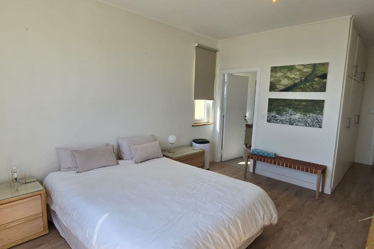 A well-lit bedroom featuring laminate flooring, neutral walls, and ample built-in cupboard storage space.