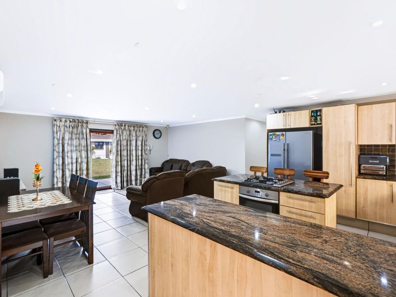 Spacious open-plan living and dining area featuring a modern kitchen with granite countertops, gas hob, and direct access to the rear patio.