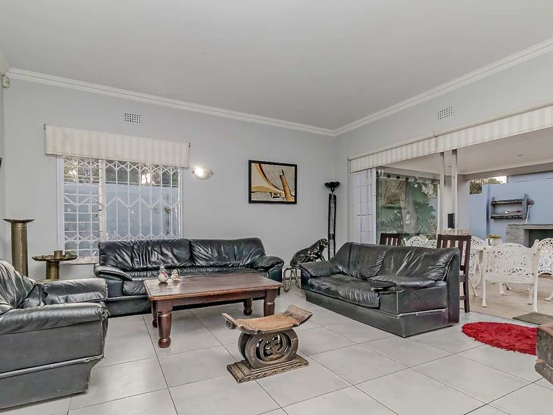 Spacious living room featuring large format floor tiles, crown molding, and sliding glass doors that open onto an outdoor patio area.