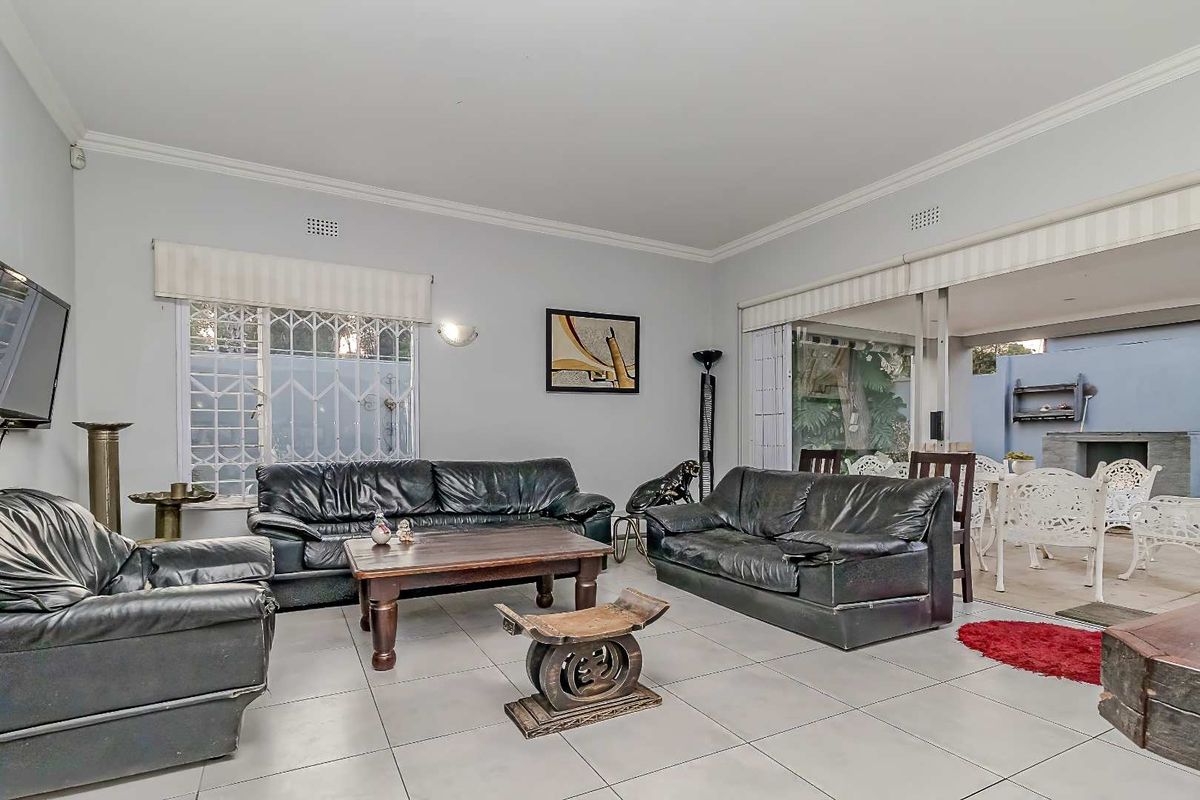 Spacious living room featuring large format floor tiles, crown molding, and sliding glass doors that open onto an outdoor patio area.