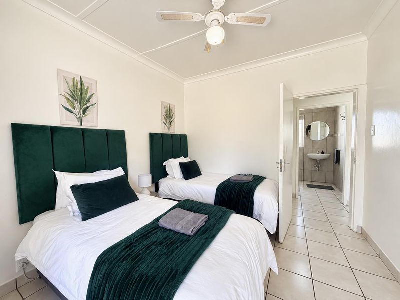 A well-maintained bedroom featuring tiled flooring, a ceiling fan, and direct access to an en-suite bathroom.