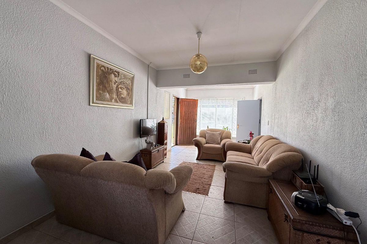 A living room featuring tiled flooring, textured walls, and a pendant light fixture, providing a functional and comfortable living space.